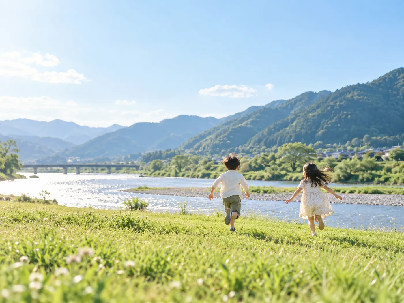 川沿いの草原を走る子どもたち